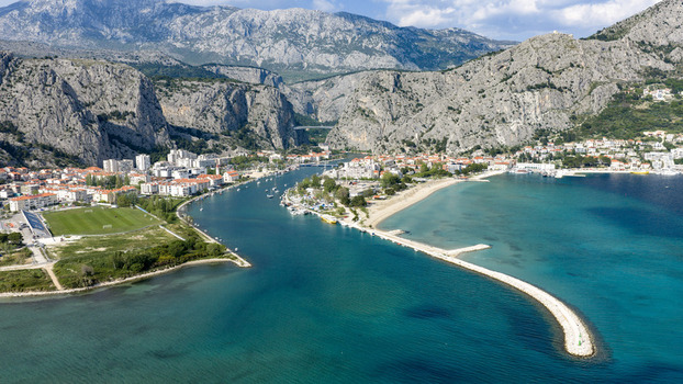 Aerial view of the coastal town of Omis featuring the Cetina river mouth dramatic limestone cliffs and turquoise Adriatic Sea waters in Omis Split Dalmatia County Croatia. Aerial view of the coastal town of Omis featuring the Cetina river mouth dramatic limestone cliffs and turquoise Adriatic Sea waters in Omis Split Dalmatia County Croatia.