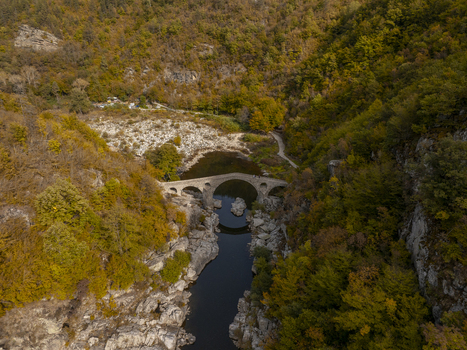 Aerial view of Devil s bridge spanning the Arda River surrounded by dense autumn forests in Kardzhali Province Bulgaria. Aerial view of Devil s bridge spanning the Arda River surrounded by dense autumn forests in Kardzhali Province Bulgaria.