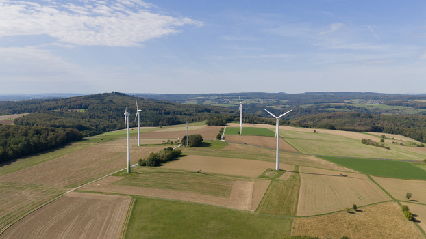 Aerial view of Windpark Eppenrod featuring wind turbines standing in agricultural fields under a blue sky in Eppenrod Rheinland Pfalz Germany.