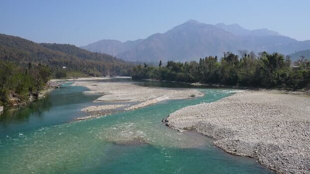 View of a turquoise river flowing through mountains in Nepal.