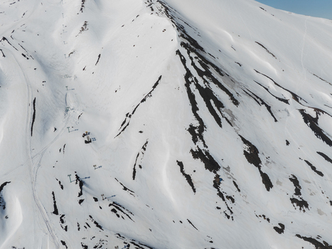 Aerial view of the snow covered slopes of Mount Etna south side with ski lift pylons and dark volcanic rock patches in Nicolosi Sicilia Italy. Aerial view of the snow covered slopes of Mount Etna south side with ski lift pylons and dark volcanic rock patches in Nicolosi Sicilia Italy.
