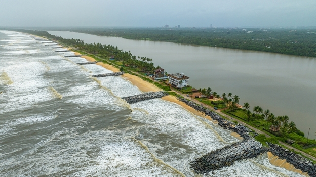 Aerial view of Mattu Beach with its distinctive stone breakwaters sandy coastline and lush palm trees separating the sea from the backwaters in Udupi Karnataka India.