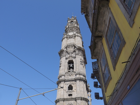 View of Clerigos Tower rising against a clear blue sky with a yellow historic building facade visible on the right in Porto Porto District Portugal. View of Clerigos Tower rising against a clear blue sky with a yellow historic building facade visible on the right in Porto Porto District Portugal.