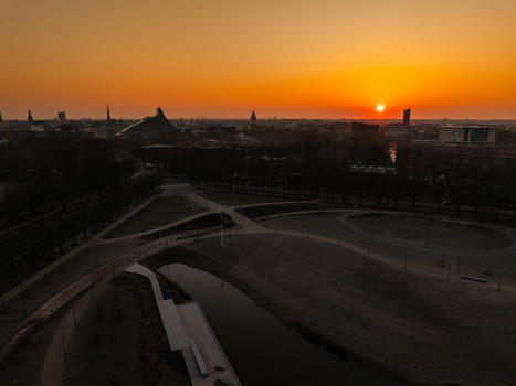 Aerial view of Uzvaras parks and the National Library of Latvia at sunset with golden light over the city skyline in Riga Latvia.