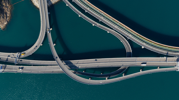 Aerial view of complex highway interchanges and bridges spanning across deep blue water with sparse vehicle traffic Hong Kong Hong Kong.