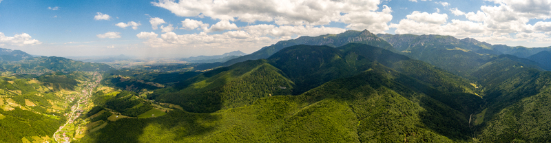 Brasov Romania 21 September 2026 Aerial view of the lush green Carpathian Mountains surrounding the city of Brasov with forested slopes and a valley settlement under a blue sky. Brasov Romania 21 September 2026 Aerial view of the lush green Carpathian Mountains surrounding the city of Brasov with forested slopes and a valley settlement under a blue sky.