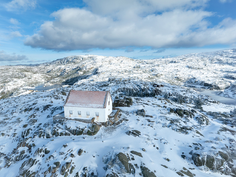 Aerial view of a solitary white house with a red roof sitting atop a snow covered hill contrasting against the blue sky Lagoa Comprida São Romão Serra da Estrella Portugal. Aerial view of a solitary white house with a red roof sitting atop a snow covered hill contrasting against the blue sky Lagoa Comprida São Romão Serra da Estrella Portugal.