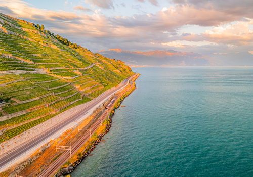 Aerial view of the terraced vineyards of Lavaux along the shores of Lake Geneva with a road and railway line at sunset in Bourg en Lavaux Vaud Switzerland. Aerial view of the terraced vineyards of Lavaux along the shores of Lake Geneva with a road and railway line at sunset in Bourg en Lavaux Vaud Switzerland.