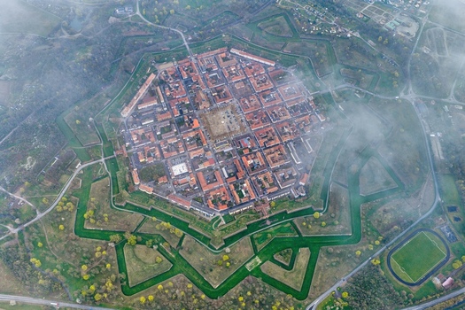 Aerial view of the star shaped fortress city a geometric marvel of red roofed buildings and lush green ramparts under a soft hazy sky Neuf Brisach Grand Est France.