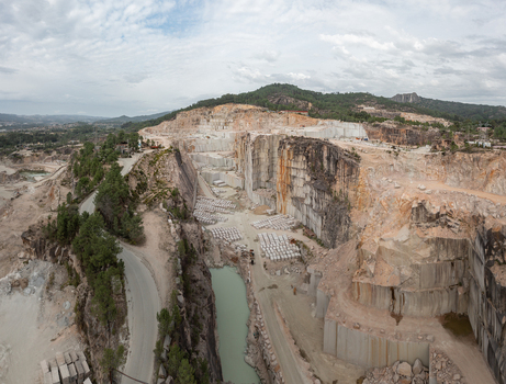 Aerial view of Cantera Porrino a large granite quarry with terraced rock faces stone blocks and a turquoise water pool in O Porrino Pontevedra Spain. Aerial view of Cantera Porrino a large granite quarry with terraced rock faces stone blocks and a turquoise water pool in O Porrino Pontevedra Spain.