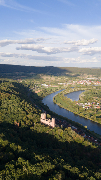 Aerial view of Burg Freudenburg overlooking the winding Main river surrounded by lush forests and the town of Freudenberg in Freudenberg Baden Wurttemberg Germany.