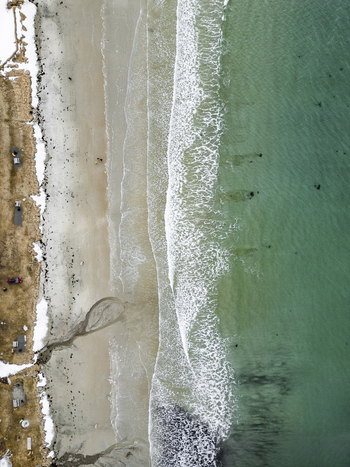 Aerial view of Grotfjord beach featuring turquoise water white waves and a snow covered shoreline in Tromvik Troms Norway. Aerial view of Grotfjord beach featuring turquoise water white waves and a snow covered shoreline in Tromvik Troms Norway.
