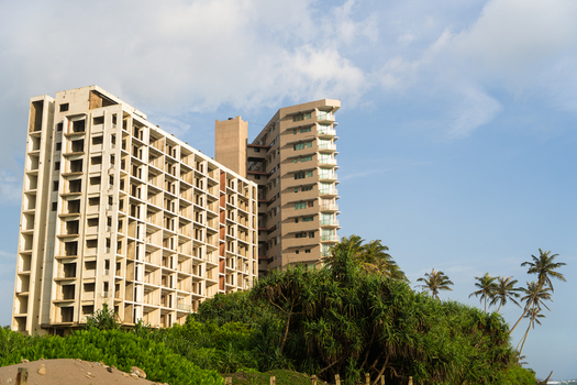 View of modern high rise apartment buildings rising above lush tropical vegetation and palm trees under a clear sky in Galle Southern Province Sri Lanka.