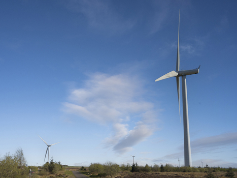 Aerial view of the wind turbines at Eaglesham moor standing tall over the green landscape under a bright blue sky Kilmarnock Scotland United Kingdom.