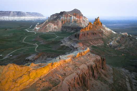 Aerial view of the dramatic rock formations of Airakty mountains in the desert landscape with winding dirt paths under golden hour light in Shetpe Mangystau Region Kazakhstan.