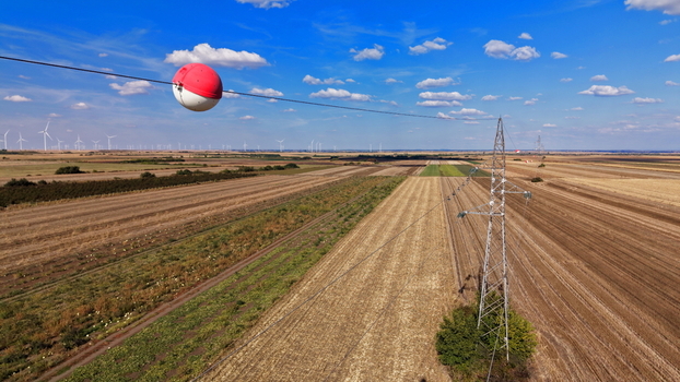 Aerial view of a signal ball on a transmission line with a pylon in a rural agricultural landscape with wind turbines in Bavaniste Vojvodina Serbia. Aerial view of a signal ball on a transmission line with a pylon in a rural agricultural landscape with wind turbines in Bavaniste Vojvodina Serbia.