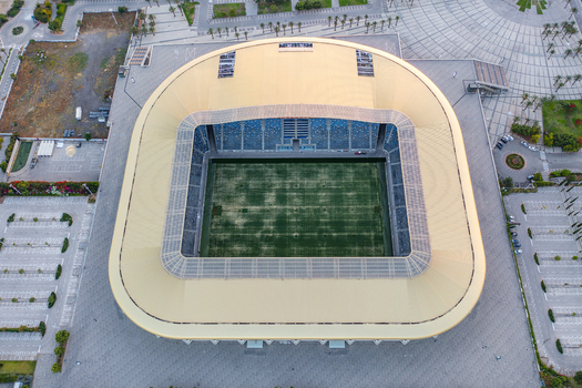 Aerial view of Sammy Ofer Stadium featuring its distinctive golden roof and green pitch surrounded by paved plazas and parking areas in Haifa Haifa District Israel. Aerial view of Sammy Ofer Stadium featuring its distinctive golden roof and green pitch surrounded by paved plazas and parking areas in Haifa Haifa District Israel.