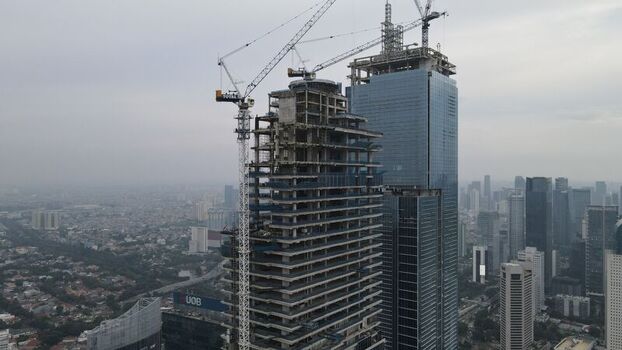 Kecamatan Menteng Indonesia 03 December 2021 Aerial view of Jakarta Pusat skyscraper under construction with a tall crane and glass facade overlooking the urban skyline. Kecamatan Menteng Indonesia 03 December 2021 Aerial view of Jakarta Pusat skyscraper under construction with a tall crane and glass facade overlooking the urban skyline.