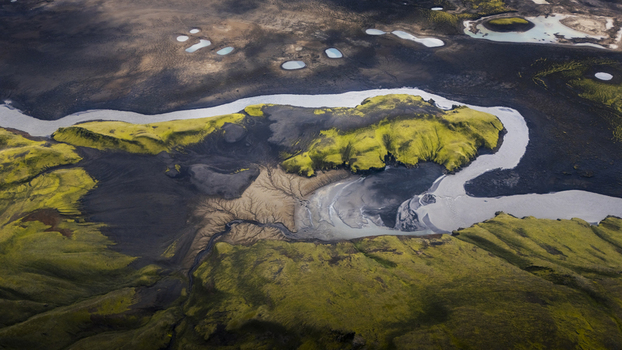Aerial view of Langisjor lake surrounded by vibrant green mossy hills dark volcanic soil and winding glacial river channels in Vik Skaftarhreppur Iceland. Aerial view of Langisjor lake surrounded by vibrant green mossy hills dark volcanic soil and winding glacial river channels in Vik Skaftarhreppur Iceland.