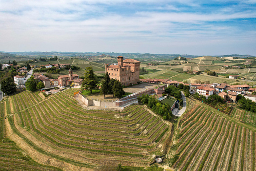 Aerial view of the medieval Castle of Grinzane Cavour surrounded by terraced vineyards and rolling hills under a bright sky Grinzane Cavour Piedmont Italy. Aerial view of the medieval Castle of Grinzane Cavour surrounded by terraced vineyards and rolling hills under a bright sky Grinzane Cavour Piedmont Italy.