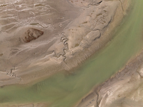 Aerial view of a meandering river carves through the textured sandy landscape creating a tranquil scene of natural artistry Abel Tasman Tasman Region New Zealand. Aerial view of a meandering river carves through the textured sandy landscape creating a tranquil scene of natural artistry Abel Tasman Tasman Region New Zealand.