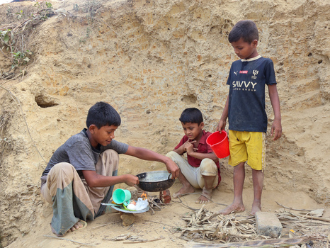 Cox s Bazar Chittagong Division Bangladesh 19 July 2026 View of three young boys cooking a meal over a small fire in a sandy outdoor area at a refugee camp. Cox s Bazar Chittagong Division Bangladesh 19 July 2026 View of three young boys cooking a meal over a small fire in a sandy outdoor area at a refugee camp.