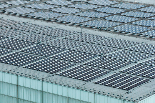 Aerial view of a large industrial building roof covered with rows of solar panels in Poland. Aerial view of a large industrial building roof covered with rows of solar panels in Poland.