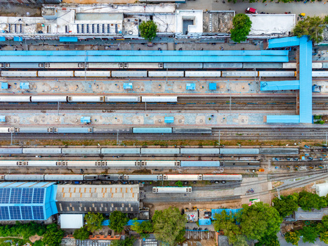 Aerial view of Udaipur Railway Station with multiple passenger trains parked at platforms under blue metal roofs in Udaipur Rajasthan India. Aerial view of Udaipur Railway Station with multiple passenger trains parked at platforms under blue metal roofs in Udaipur Rajasthan India.