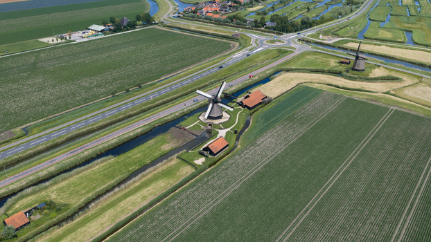 Aerial view of De Museummolen surrounded by lush green fields canals and a nearby road in Schermerhorn Noord Holland Netherlands. Aerial view of De Museummolen surrounded by lush green fields canals and a nearby road in Schermerhorn Noord Holland Netherlands.