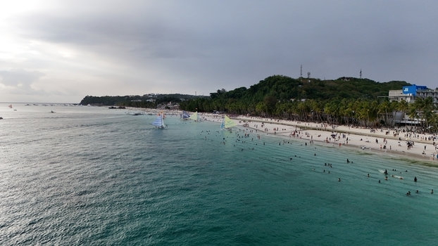 Malay Philippines 02 May 2026 Aerial view of Boracay Island with people swimming sailboats on turquoise water and palm trees along the white sand beach.