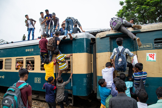 Dhaka Bangladesh 14 June 2018 View of people climbing onto the roof and sides of a crowded passenger train at Airport Railway Station during the Eid al Fitr holiday rush. Dhaka Bangladesh 14 June 2018 View of people climbing onto the roof and sides of a crowded passenger train at Airport Railway Station during the Eid al Fitr holiday rush.