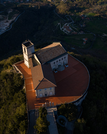 Aerial view of Santuario del Santissimo Salvatore with its terracotta terrace and historic architecture overlooking lush green hills at sunset in Montella Campania Italy. Aerial view of Santuario del Santissimo Salvatore with its terracotta terrace and historic architecture overlooking lush green hills at sunset in Montella Campania Italy.