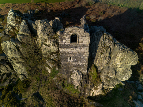 Aerial view of the historic Roche Rock stone chapel perched on a rugged granite outcrop surrounded by moorland in Roche Cornwall United Kingdom. Aerial view of the historic Roche Rock stone chapel perched on a rugged granite outcrop surrounded by moorland in Roche Cornwall United Kingdom.