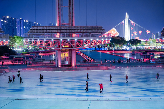 Guangzhou Guangdong Province China 24 February 2024 View of people walking across the illuminated plaza at night with the Haixinsha bridge and modern city skyline in the background. Guangzhou Guangdong Province China 24 February 2024 View of people walking across the illuminated plaza at night with the Haixinsha bridge and modern city skyline in the background.