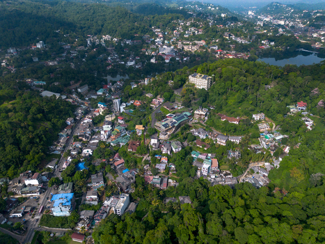 Aerial view of Kandy Lake surrounded by lush green hills dense residential buildings and winding roads in Kandy Central Province Sri Lanka. Aerial view of Kandy Lake surrounded by lush green hills dense residential buildings and winding roads in Kandy Central Province Sri Lanka.