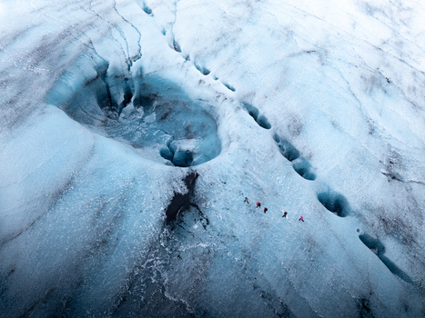 Aerial view of Breidamerkurjokull glacier with hikers walking across the blue ice surface in Sveitarfelagid Hornafjordur Iceland. Aerial view of Breidamerkurjokull glacier with hikers walking across the blue ice surface in Sveitarfelagid Hornafjordur Iceland.