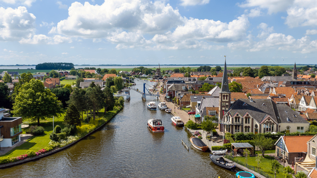 Aerial view of the picturesque village of Woudsend with its canal historic buildings church tower and boats under a bright blue sky in Woudsend Friesland Netherlands. Aerial view of the picturesque village of Woudsend with its canal historic buildings church tower and boats under a bright blue sky in Woudsend Friesland Netherlands.