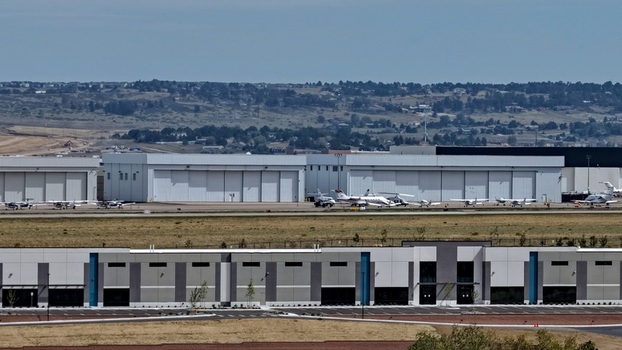 Aerial view of Centennial Airport with rows of large aircraft hangars and private jets parked on the tarmac in Centennial Colorado United States.