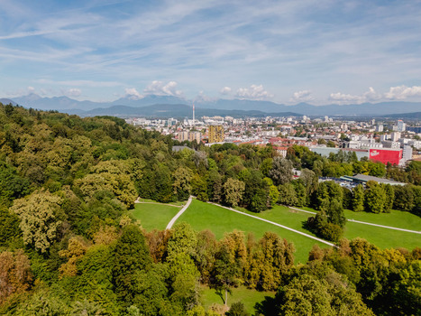 Aerial view of Tivoli Park featuring lush green lawns dense trees and winding pathways with the city skyline in the background Ljubljana Slovenia.
