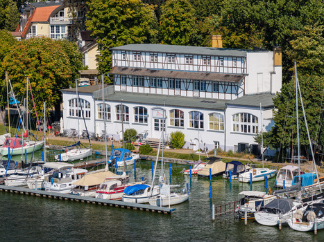 Aerial view of Yachtclub Wendenschloss e.V. with numerous sailboats moored at the marina featuring a historic timber framed building along the waterfront in Berlin Berlin Germany. Aerial view of Yachtclub Wendenschloss e.V. with numerous sailboats moored at the marina featuring a historic timber framed building along the waterfront in Berlin Berlin Germany.