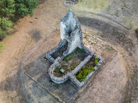 Aerial view of the medieval Csabdi church ruins with weathered stone walls an arched sanctuary and overgrown foundations in a dry rural clearing in Hungary.