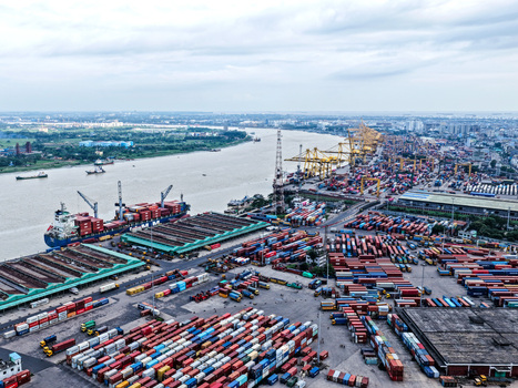 Aerial view of the busy Chattogram Port featuring numerous shipping containers industrial cranes and cargo ships docked along the river in Chittagong Chittagong Division Bangladesh.