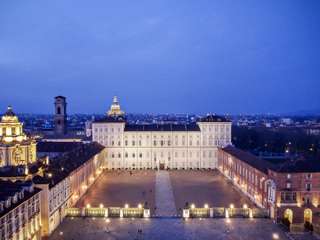 Aerial view of the illuminated Royal Palace of Turin and Piazza Castello with historic domes under a deep blue twilight sky in Turin Piedmont Italy.
