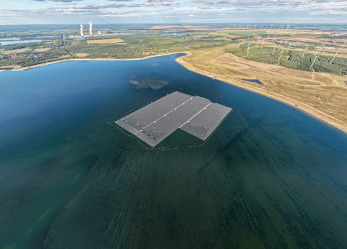 Aerial view of the floating solar park on Cottbuser Ostsee a former open pit mine with the Janschwalde Power Plant and wind turbines in the background in Cottbus Brandenburg Germany. Aerial view of the floating solar park on Cottbuser Ostsee a former open pit mine with the Janschwalde Power Plant and wind turbines in the background in Cottbus Brandenburg Germany.