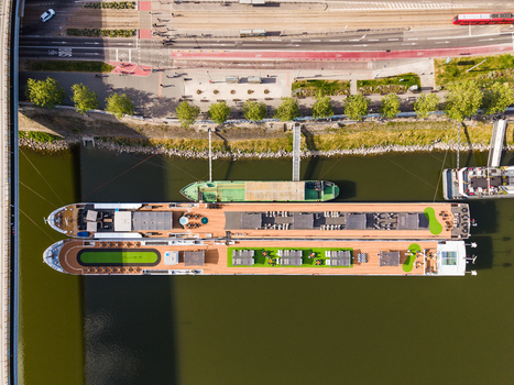 Aerial view of two river cruise ships docked along the Danube riverbank with a road and green trees in Bratislava Bratislava Region Slovakia. Aerial view of two river cruise ships docked along the Danube riverbank with a road and green trees in Bratislava Bratislava Region Slovakia.