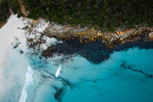 Aerial view of Bettys Beach featuring turquoise water white sand rocky coastline and dense green vegetation in Albany WA Australia. Aerial view of Bettys Beach featuring turquoise water white sand rocky coastline and dense green vegetation in Albany WA Australia.