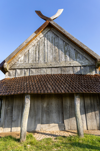 View of the Viking Fortress Trelleborg featuring traditional wooden architecture with a gabled roof and curved support posts in Slagelse Sjaeland Denmark. View of the Viking Fortress Trelleborg featuring traditional wooden architecture with a gabled roof and curved support posts in Slagelse Sjaeland Denmark.