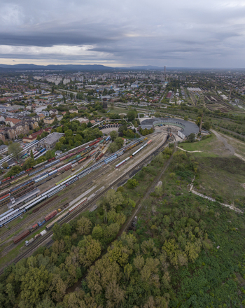 Aerial view of the Hungarian Railway Museum featuring its iconic roundhouse extensive train tracks with various freight cars and surrounding greenery in Budapest Hungary. Aerial view of the Hungarian Railway Museum featuring its iconic roundhouse extensive train tracks with various freight cars and surrounding greenery in Budapest Hungary.