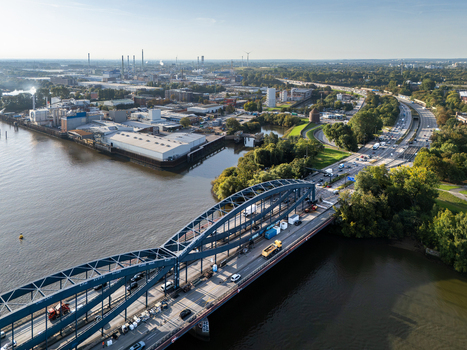 Aerial view of the Elbbrucken bridge in Hamburg showing traffic on the steel arch structure the Elbe river industrial buildings and green surroundings in Hamburg Germany.