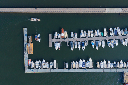 Aerial view of the marina in Como with numerous boats docked at wooden piers calm dark water and clear daylight in Como Lombardy Italy.